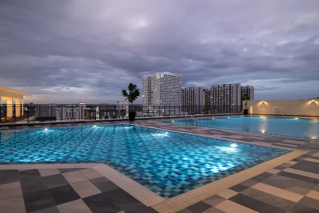 Asteria Melaka's lit pool deck at dusk with the towers behind.